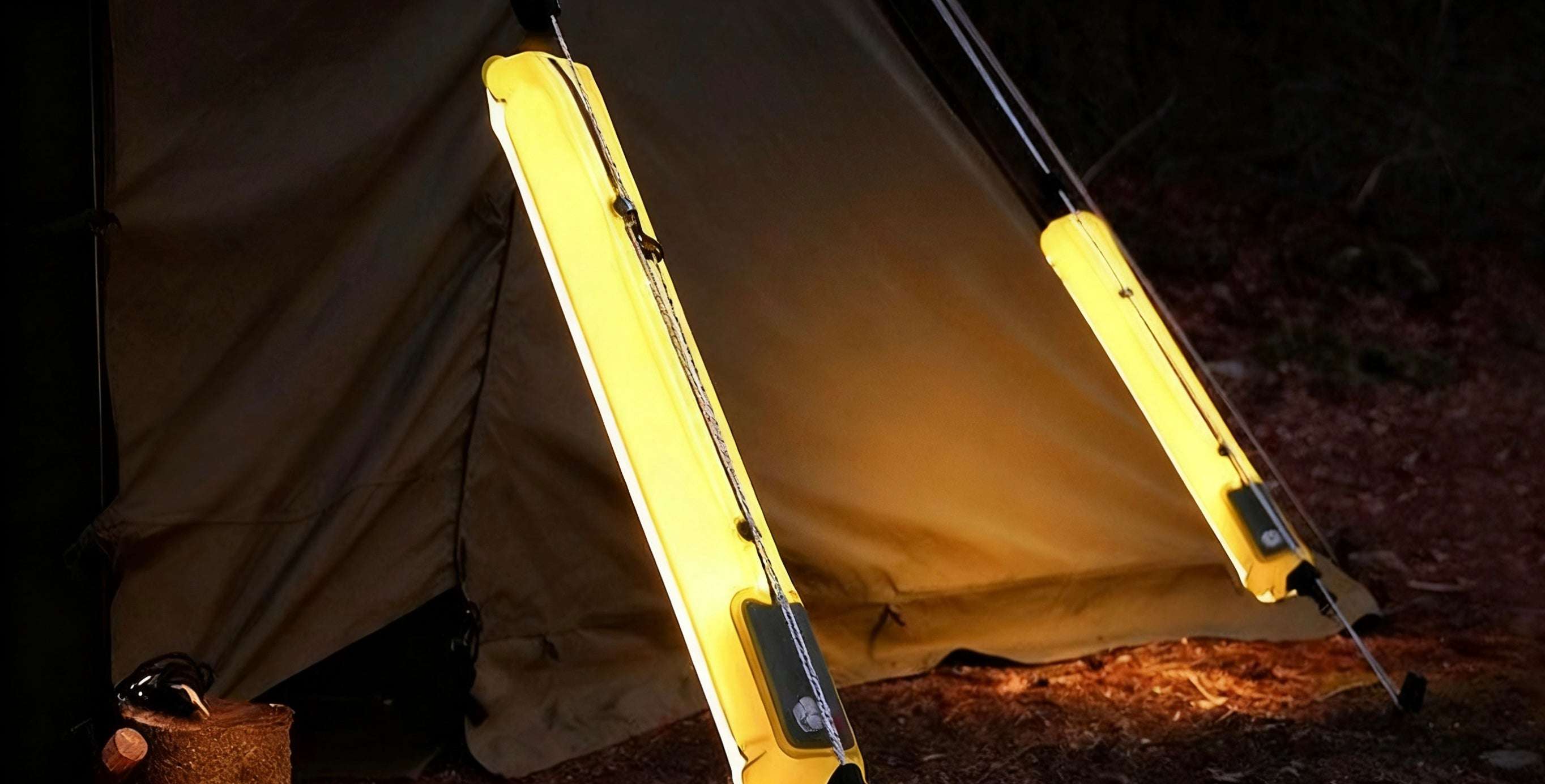 Yellow camping light attached to a tent in a dark outdoor setting
