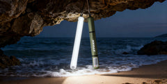 Two light tubes hanging from a rock over a beach with ocean waves.