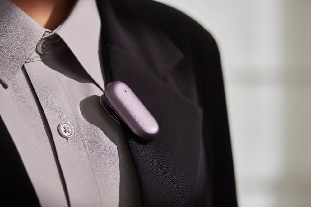 Purple Plaud Note device clip on the pocket of a gray suit jacket