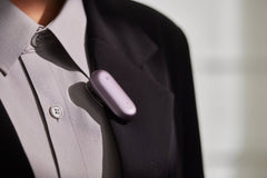 Purple Plaud Note device clip on the pocket of a gray suit jacket