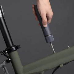 Hand using a tool on a bicycle frame against a dark background