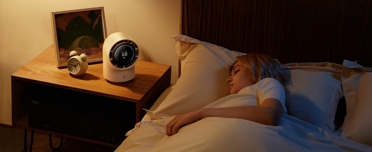 Person lying in bed with a nightstand featuring a smart clock and alarm.
