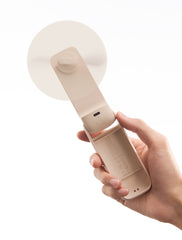 Hand holding a beige kitchen tool with a white suction cup on a white background