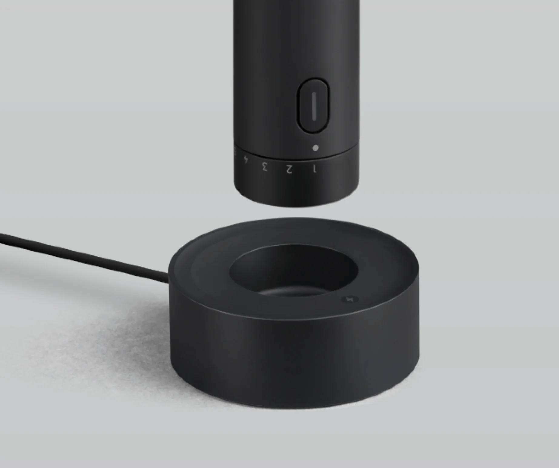 Black electronic device with a cylindrical top and circular base on a light gray background