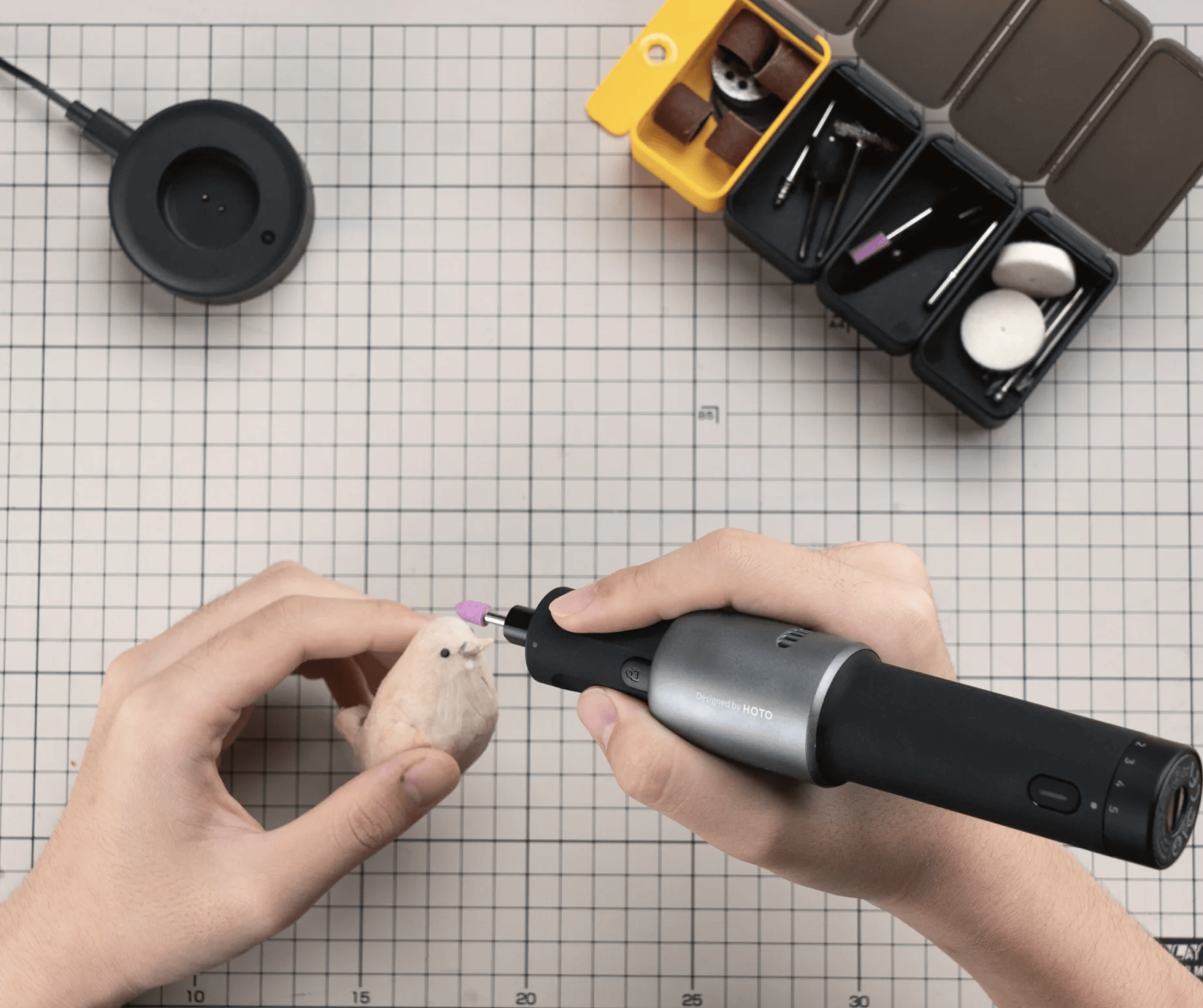 Person using a small tool on a stuffed animal with a grid background