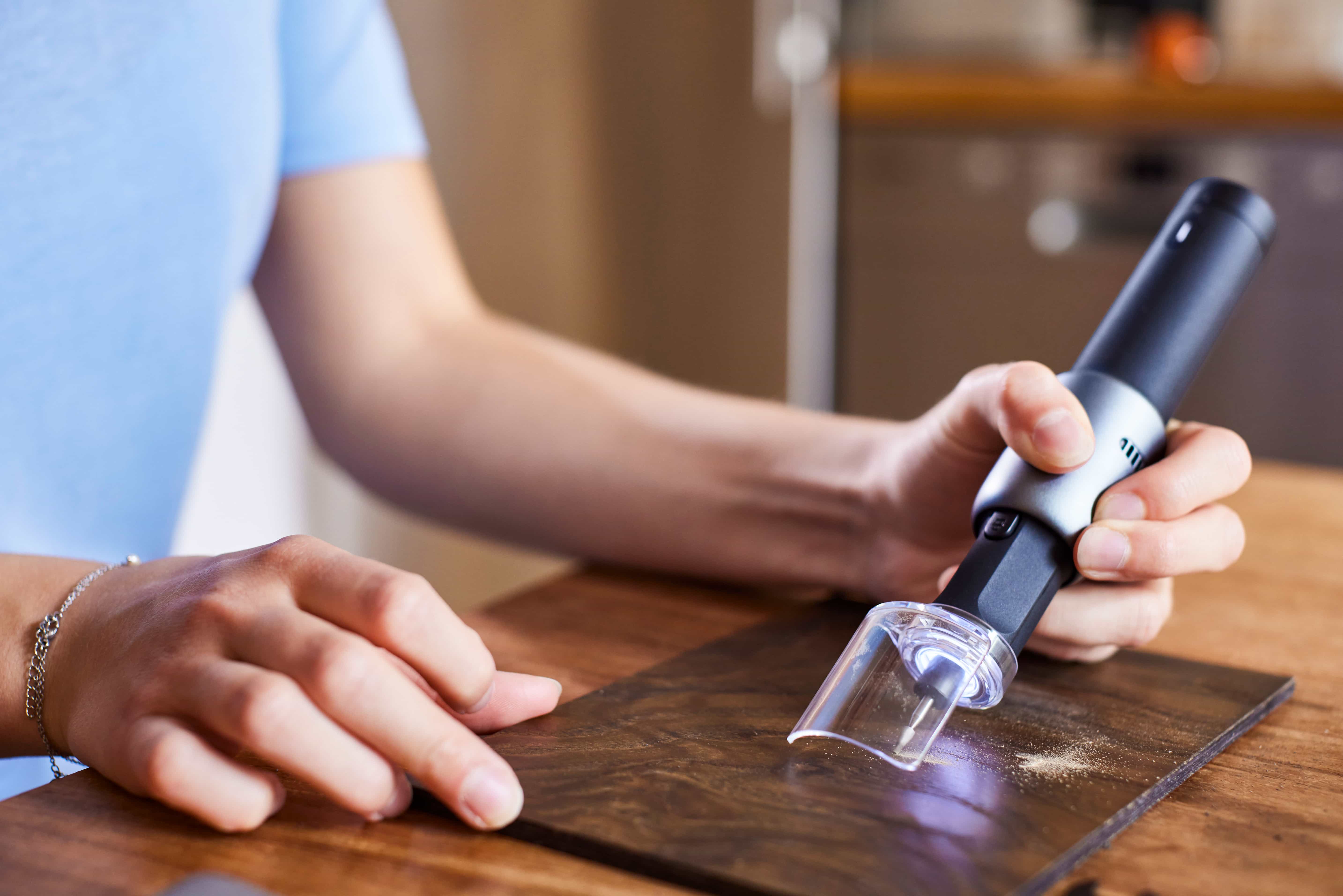 Person using a handheld tool on a wooden surface