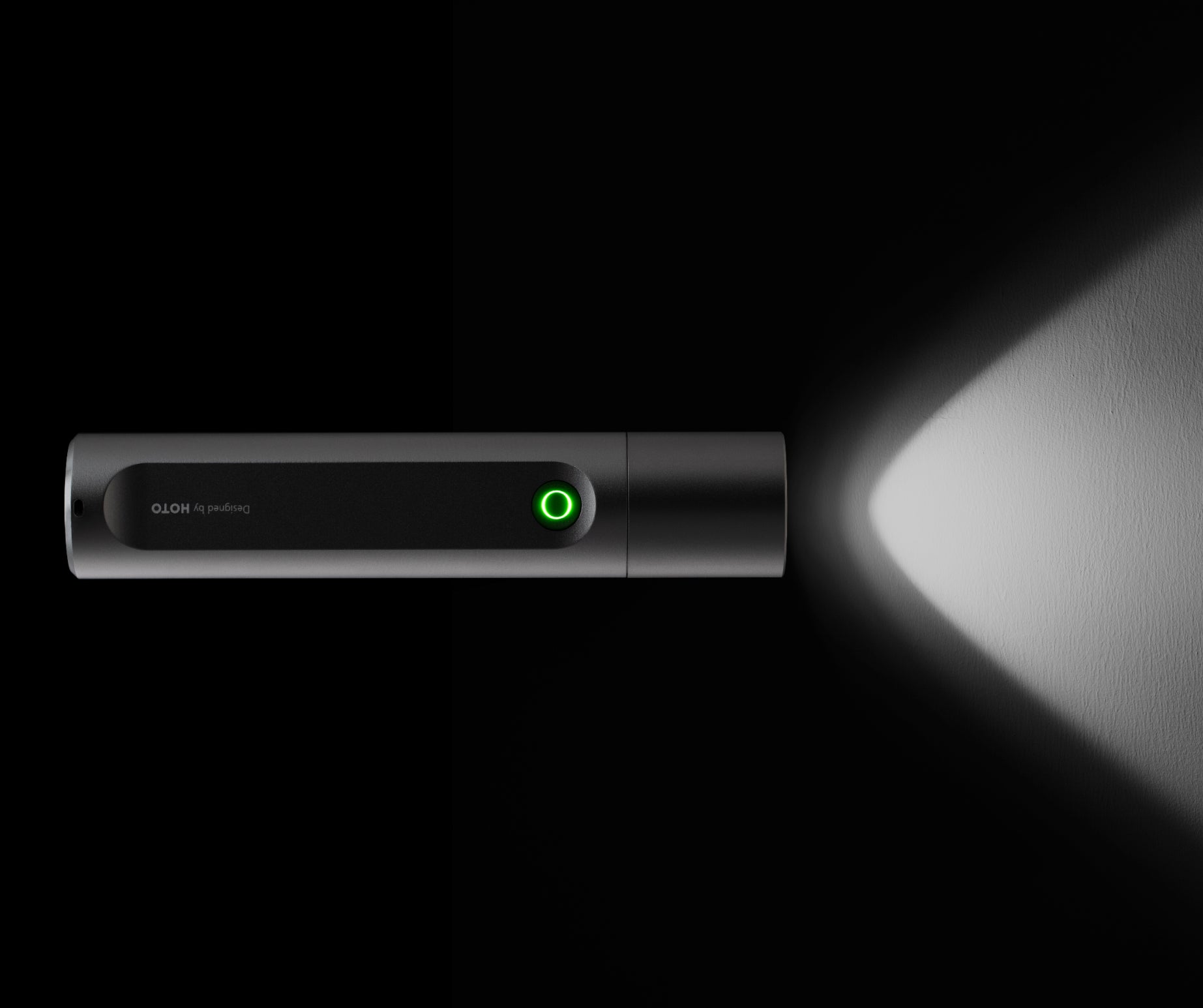 Black flashlight with a green light on a black background