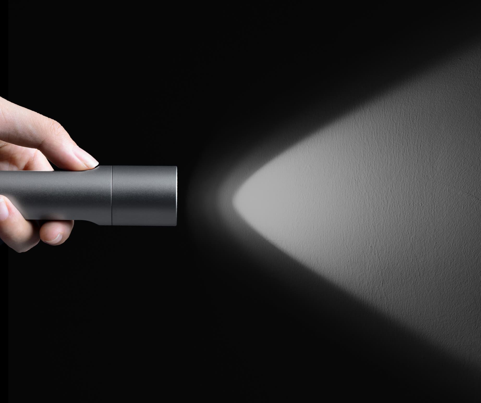 Hand holding a flashlight against a dark background