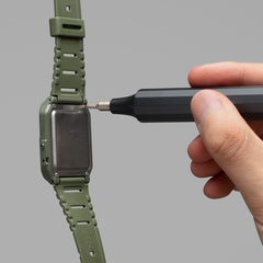 Person using a screwdriver to adjust the band of a green smartwatch on a gray background