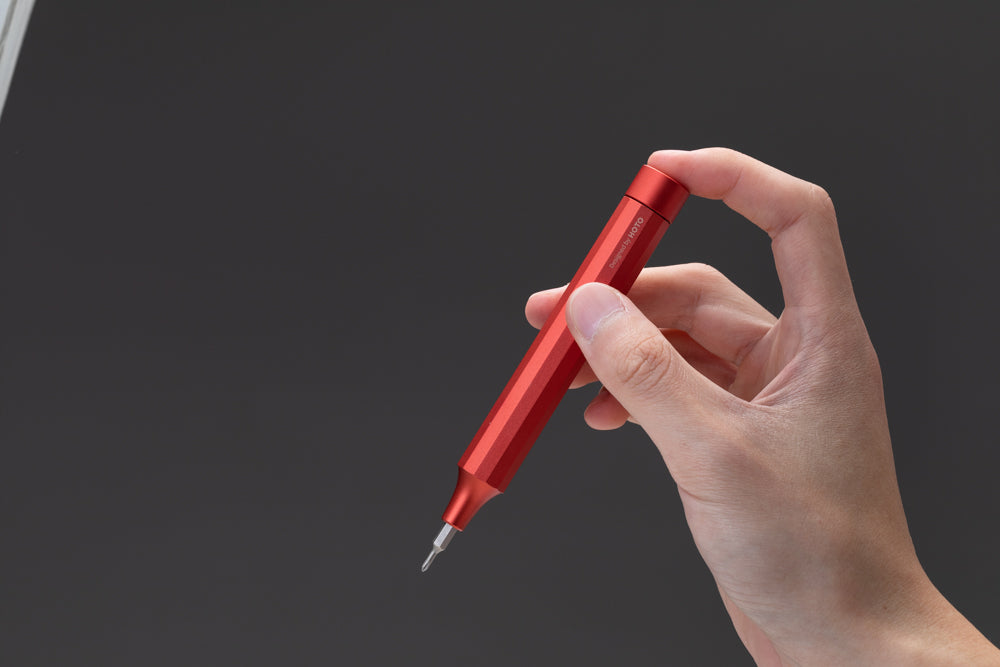 Hand holding a red pen against a dark background