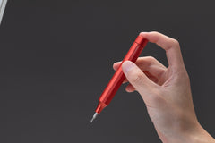 Hand holding a red pen against a dark background