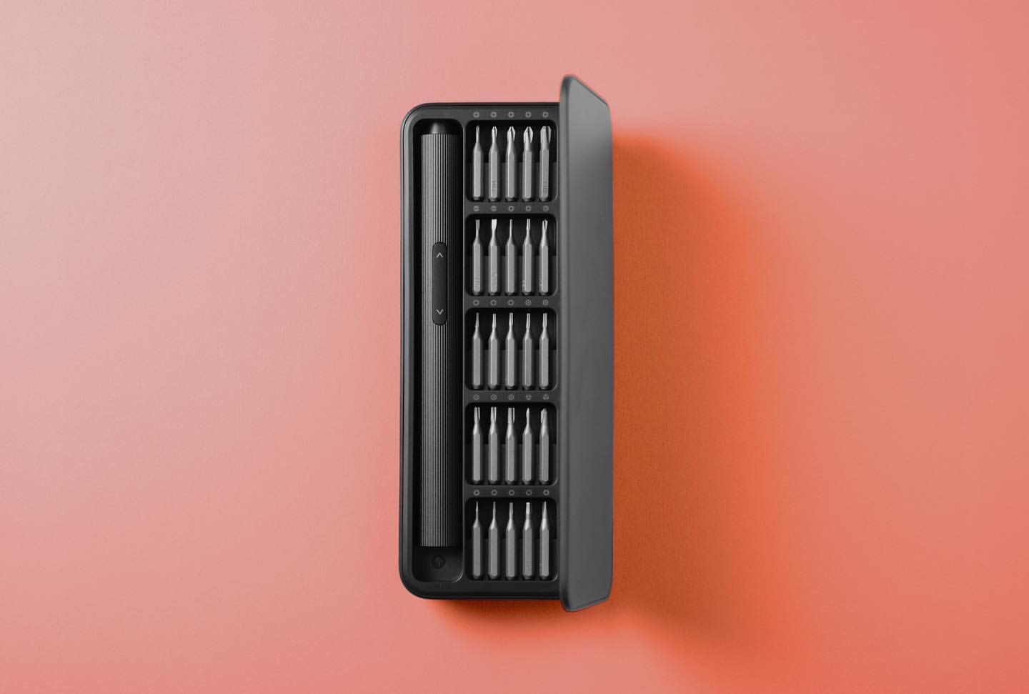 Black screwdriver set in a compact case on a gradient pink background