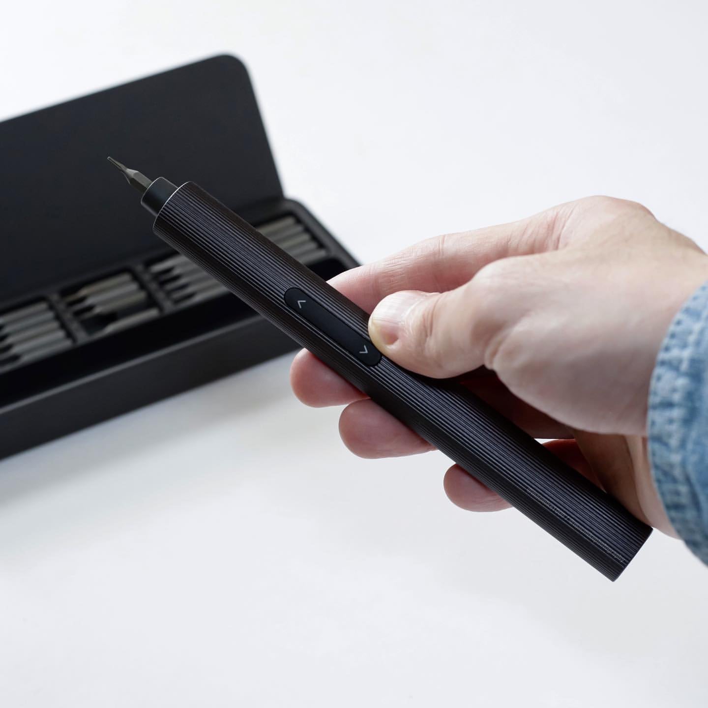 Hand holding a black stylus pen with a blurred background
