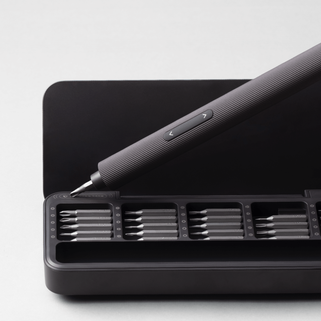 Black screwdriver set with multiple bits on a white background