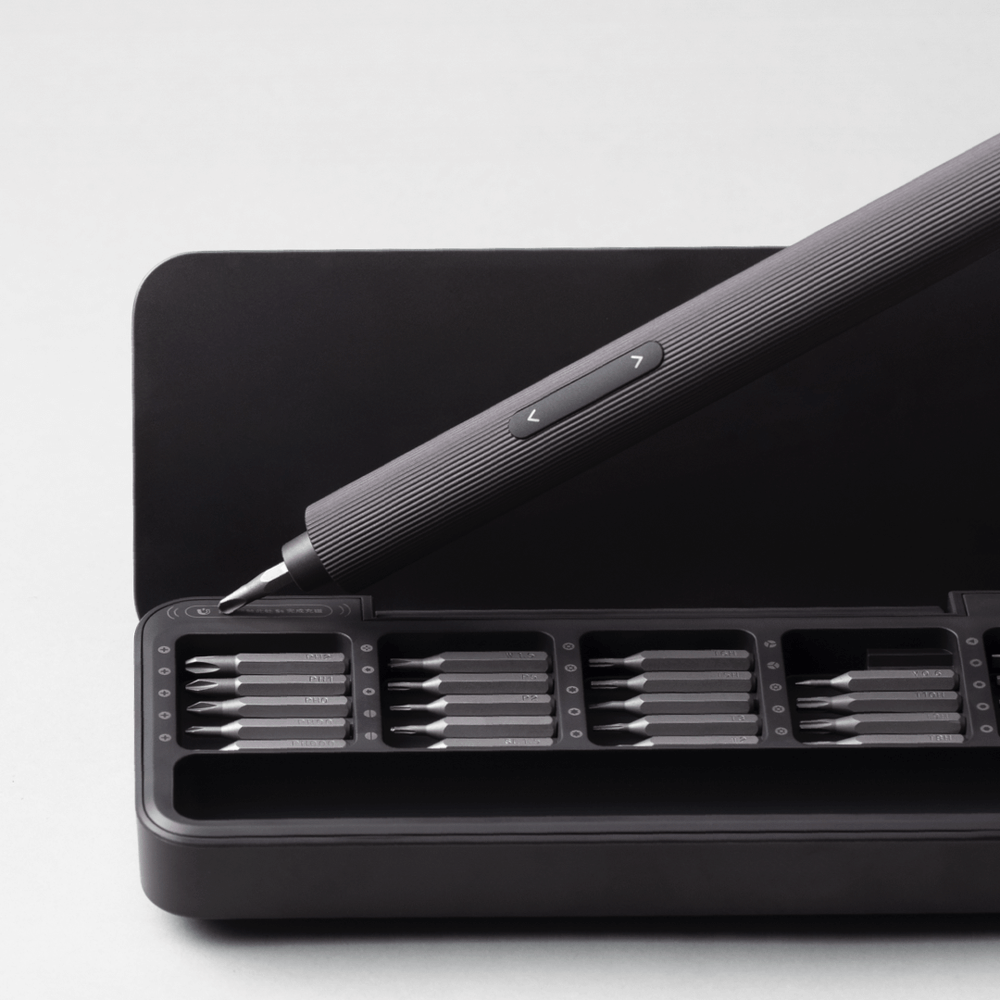 Black screwdriver set with multiple bits on a white background