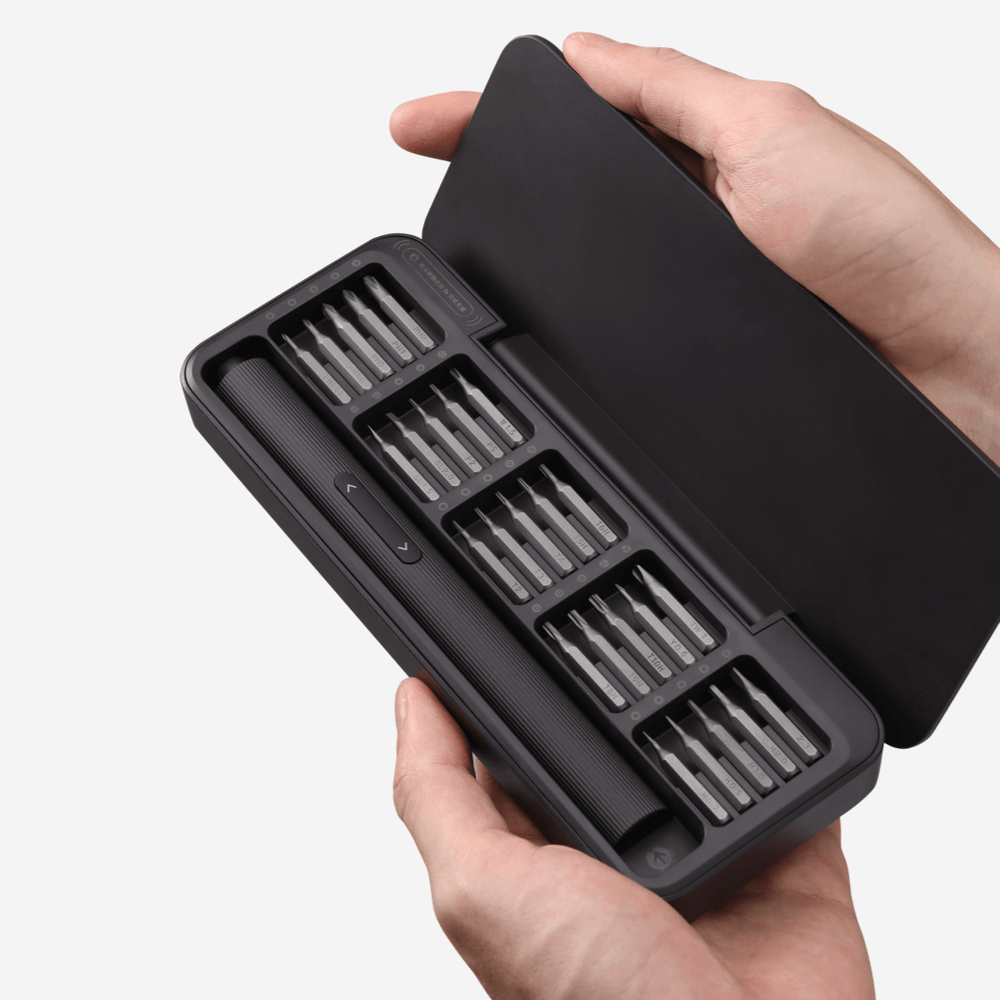 Black screwdriver set in a case held by a hand on a white background