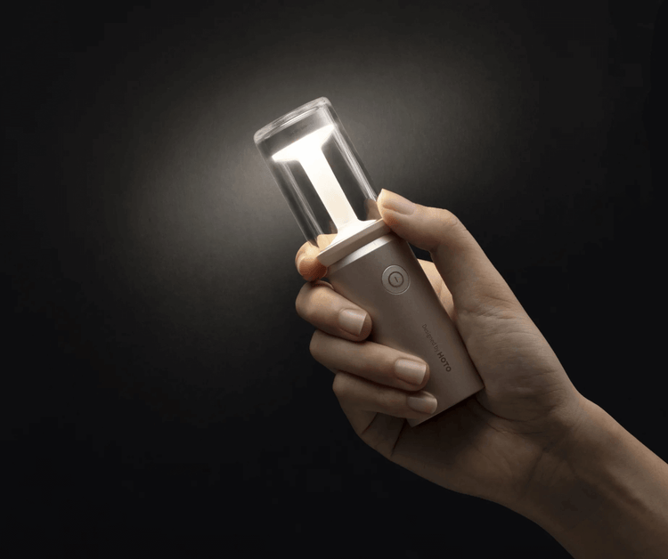 Hand holding a portable light source against a dark background