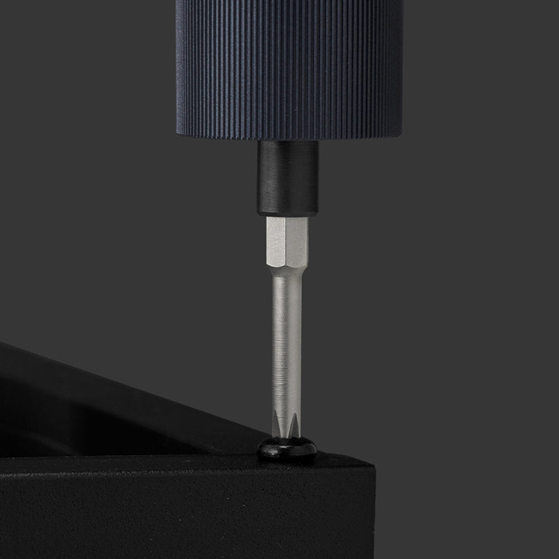 Close-up of a black screwdriver bit attached to a black handle on a gray background