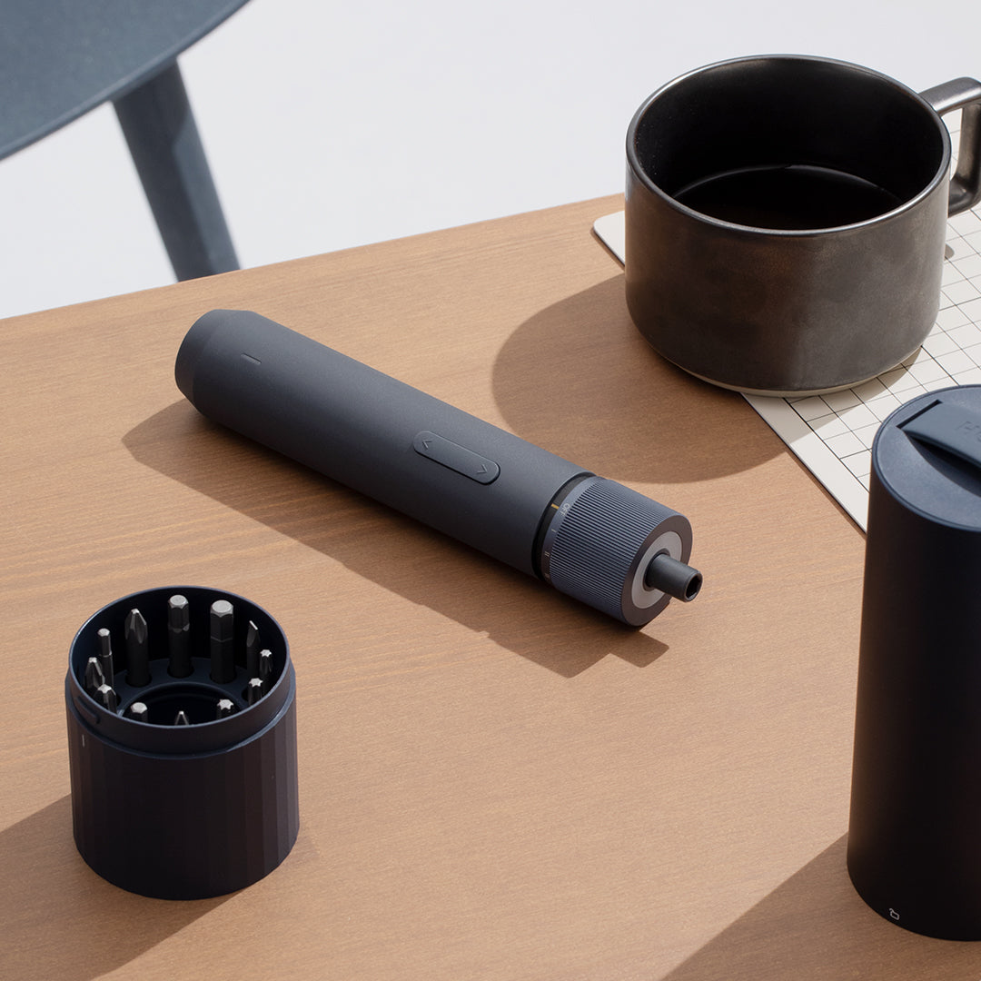 Gray handheld device with black attachments on a wooden surface