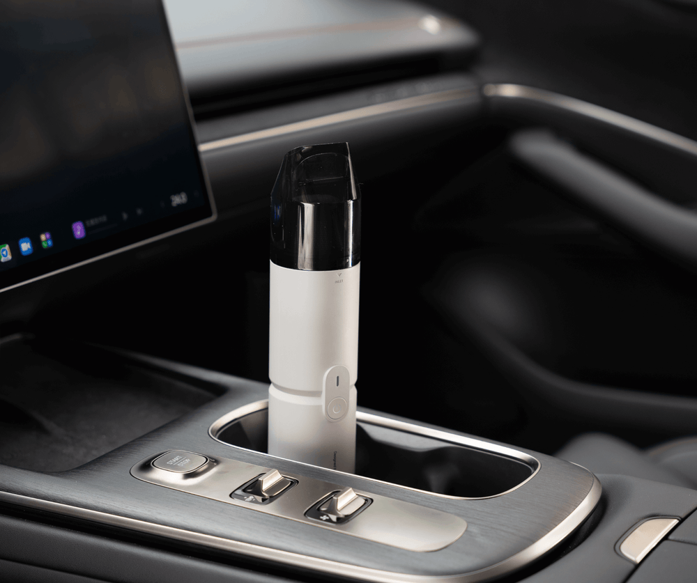 Car cup holder with a white electronic device inside, likely a vape pen, on a dark interior background.
