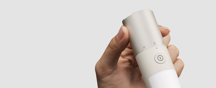 Hand holding a white electronic device with a gray background