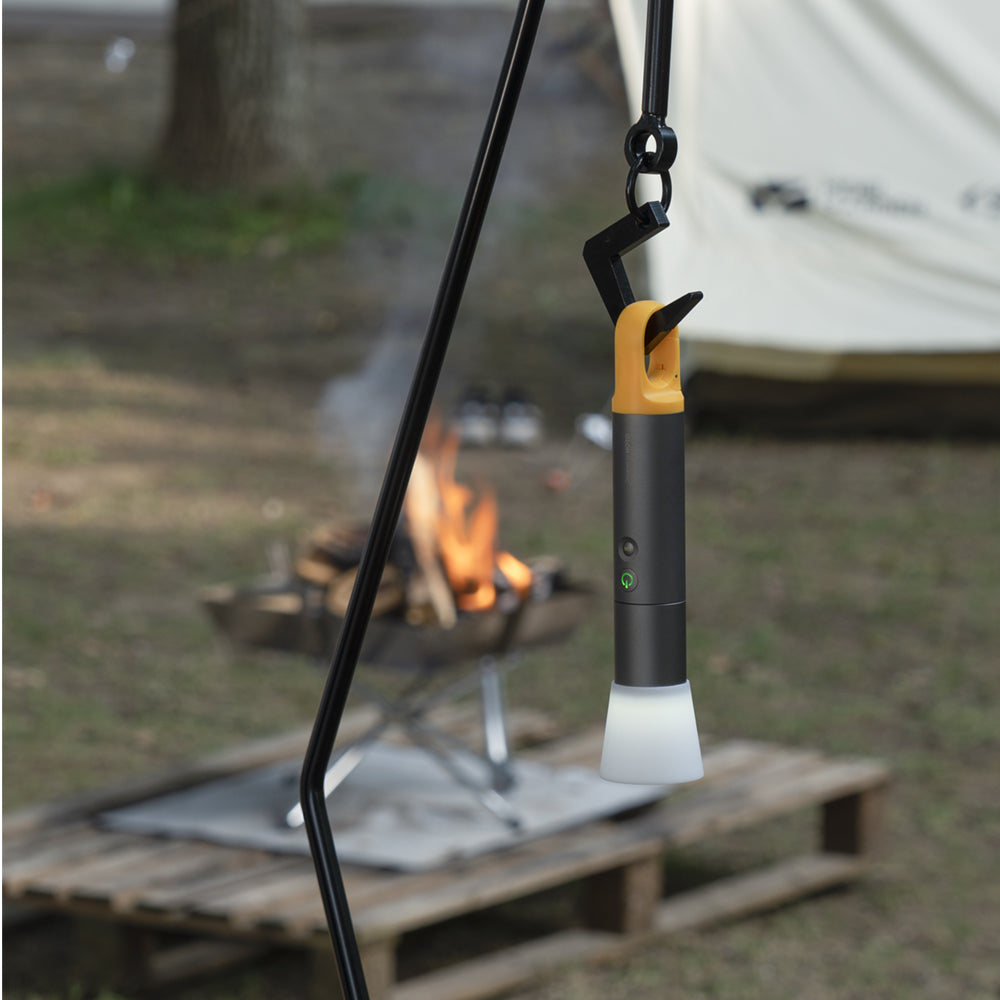 Camping lantern hanging over a campfire with a blurred background