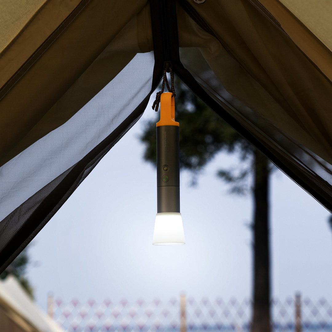 Portable light hanging from a tent canopy with trees in the background