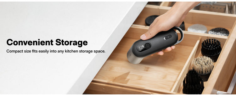 Hand holding a black kitchen tool over a wooden drawer with compartments.