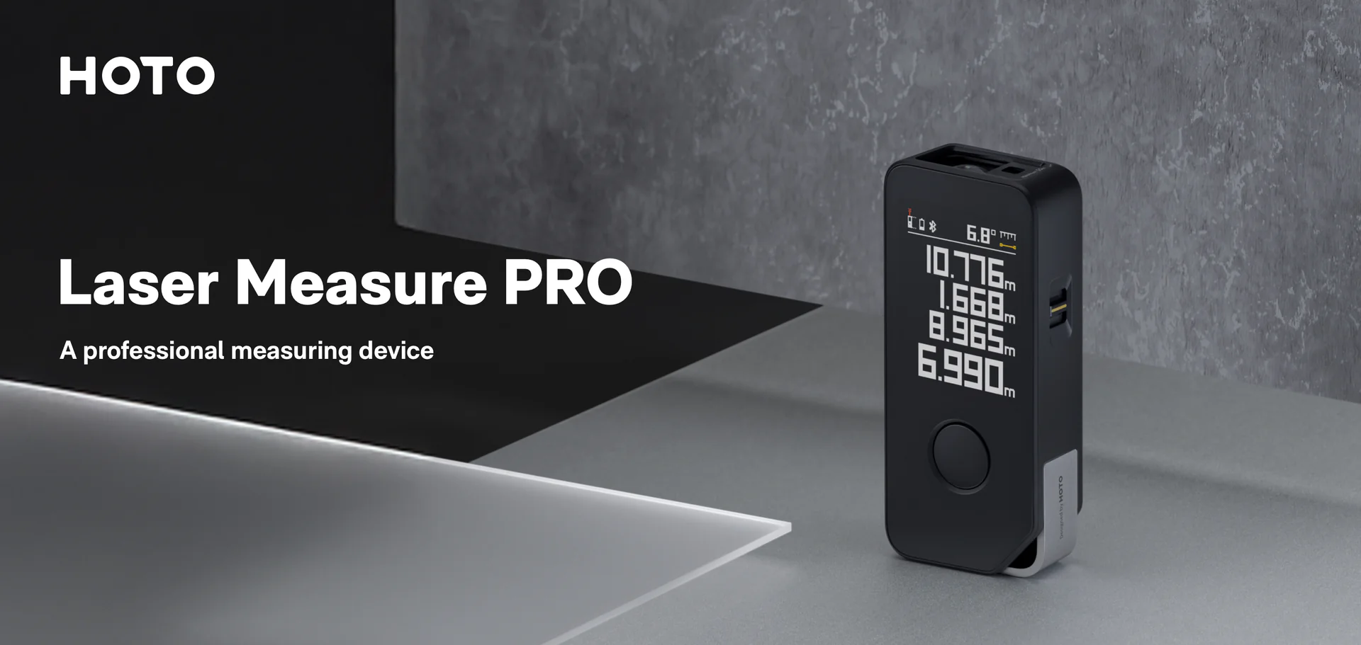HOTO Laser Measure PRO device on a gray surface with a dark background
