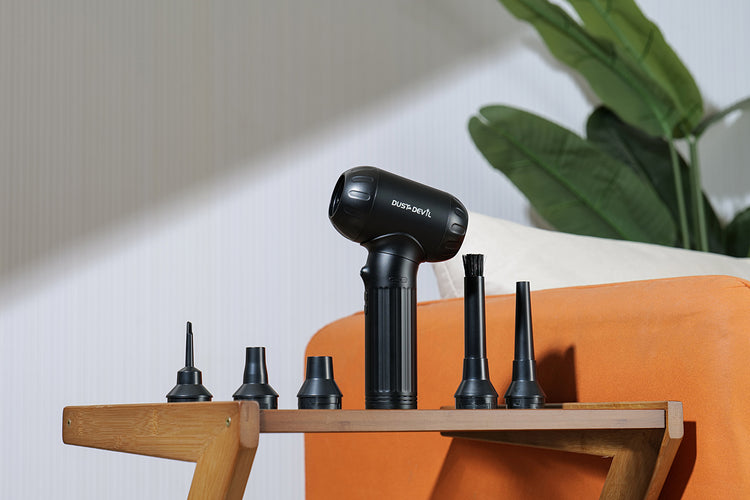 Dust Devil air duster with multiple nozzle attachments displayed on a wooden shelf, highlighting the versatility of the cleaning tool